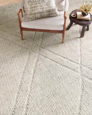 Textured white rug with wooden chair and small round table.